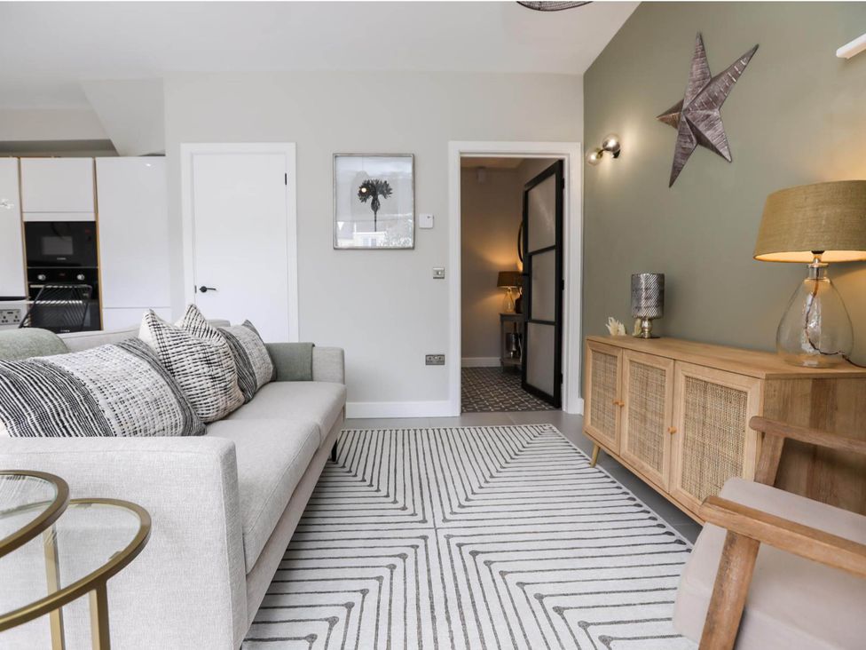 A living room with a sofa and a wooden cabinet at Luxury 2 Bed Home w/ Spa-like Ensuites & Patio in Hereford