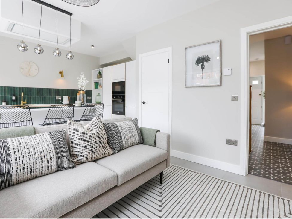 A living room with a sofa and kitchen area at Luxury 2 Bed Home w/ Spa-like Ensuites & Patio in Hereford