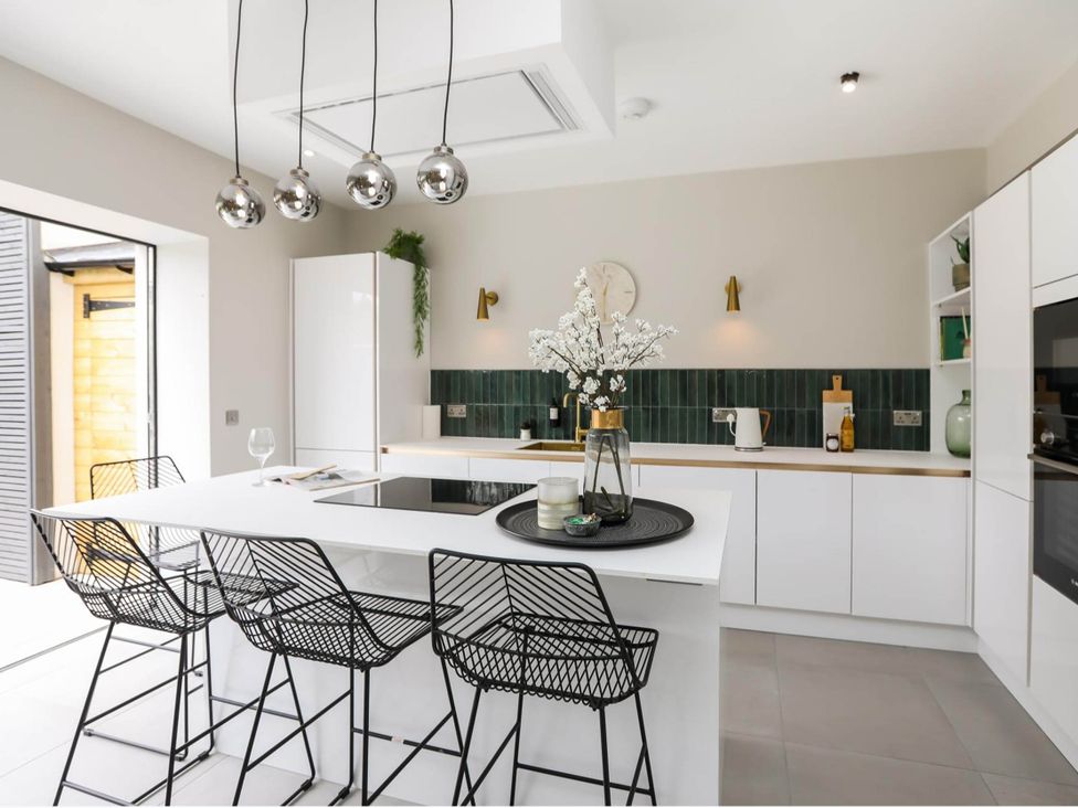 A kitchen with white cabinets and bar stools at Luxury 2 Bed Home w/ Spa-like Ensuites & Patio, Hereford