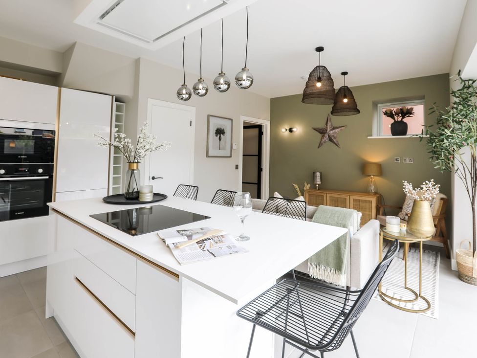 A kitchen with an island, oven, black chairs, and a sofa at Luxury 2 Bed Home w/ Spa-like Ensuites & Patio Hereford