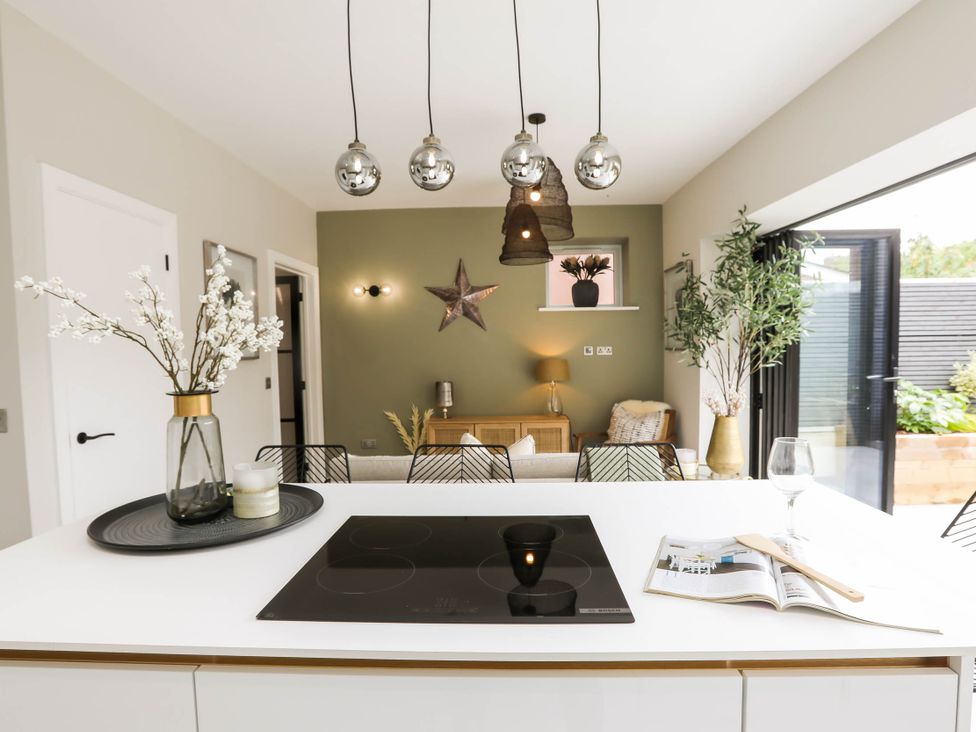 A kitchen with a cooktop and a dining area at Luxury 2 Bed Home w/ Spa-like Ensuites & Patio Hereford