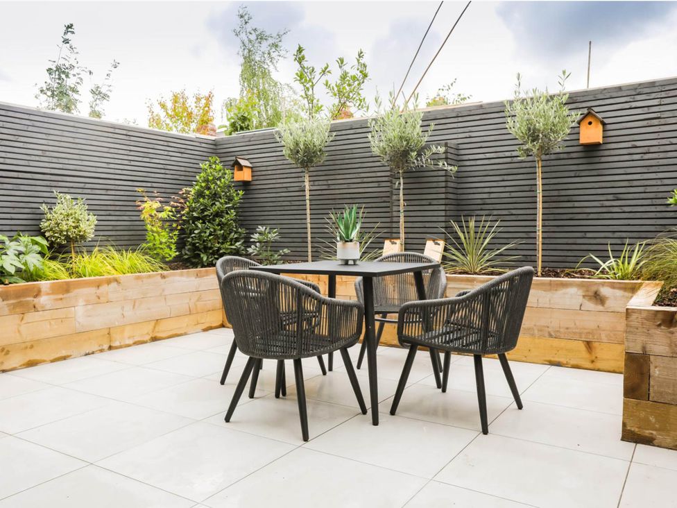A garden with a table and chairs surrounded by plants at Luxury 2 Bed Home w/ Spa-like Ensuites & Patio Hereford
