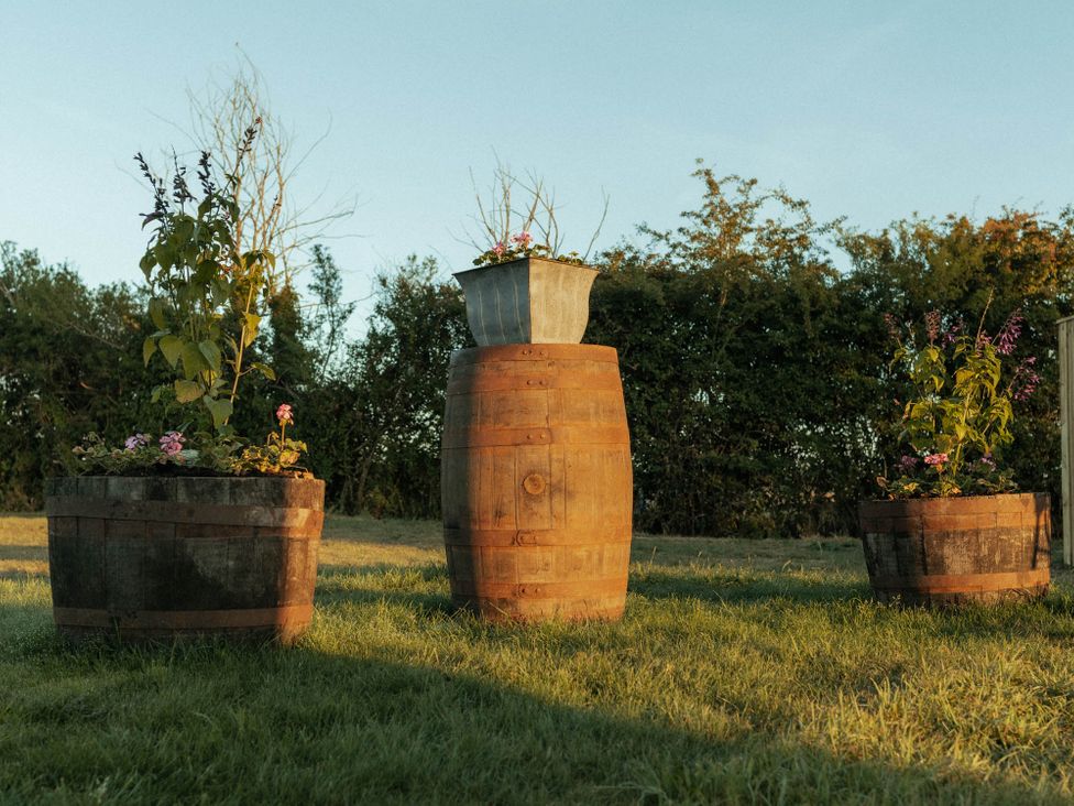 Planters made from barrels with flowers in a garden at Glamping at the Retreat Wiltshire is rural bliss Christian Malford