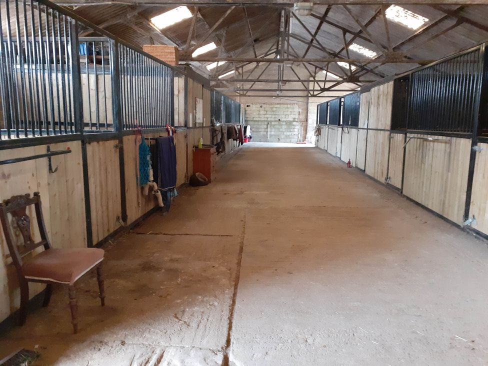 A stable with horse stalls and a chair at Glamping at the Retreat Wiltshire Christian Malford