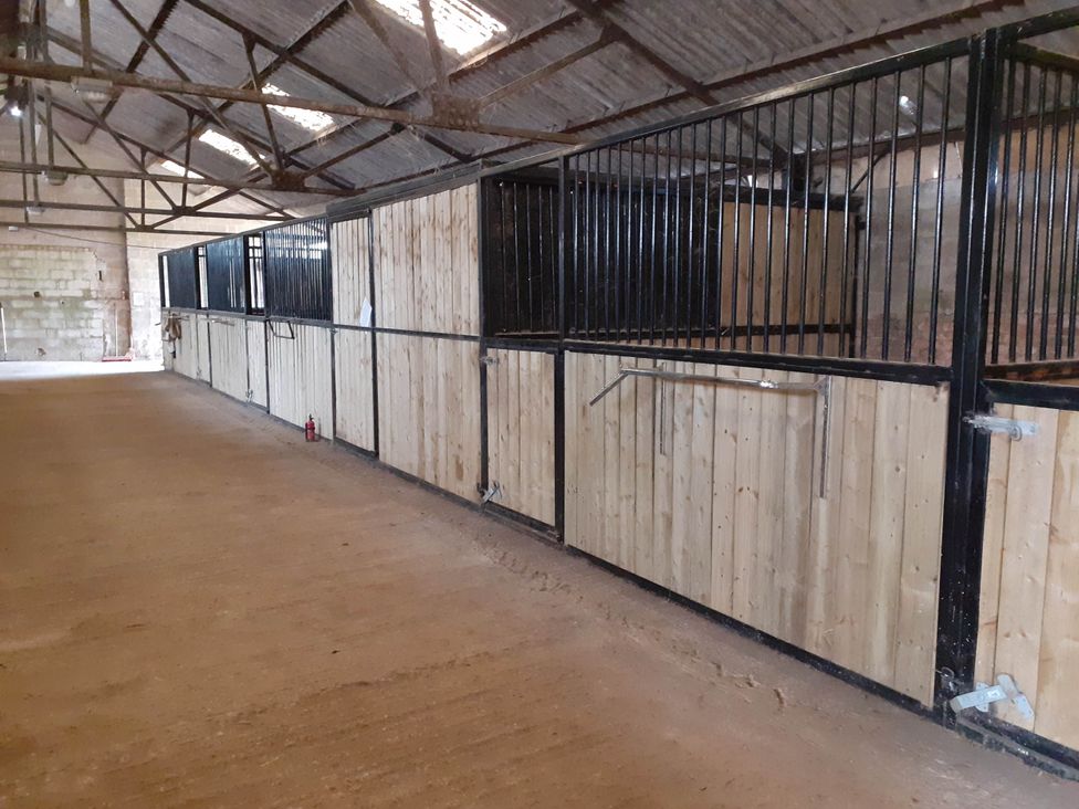 A row of stables with wooden partitions and metal bars at Glamping at the Retreat Wiltshire is rural bliss Christian Malford
