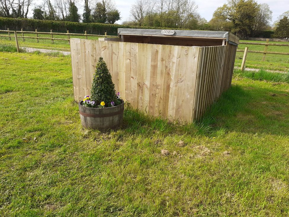 A wooden structure with a planter near grass at Glamping at the Retreat Wiltshire in Christian Malford