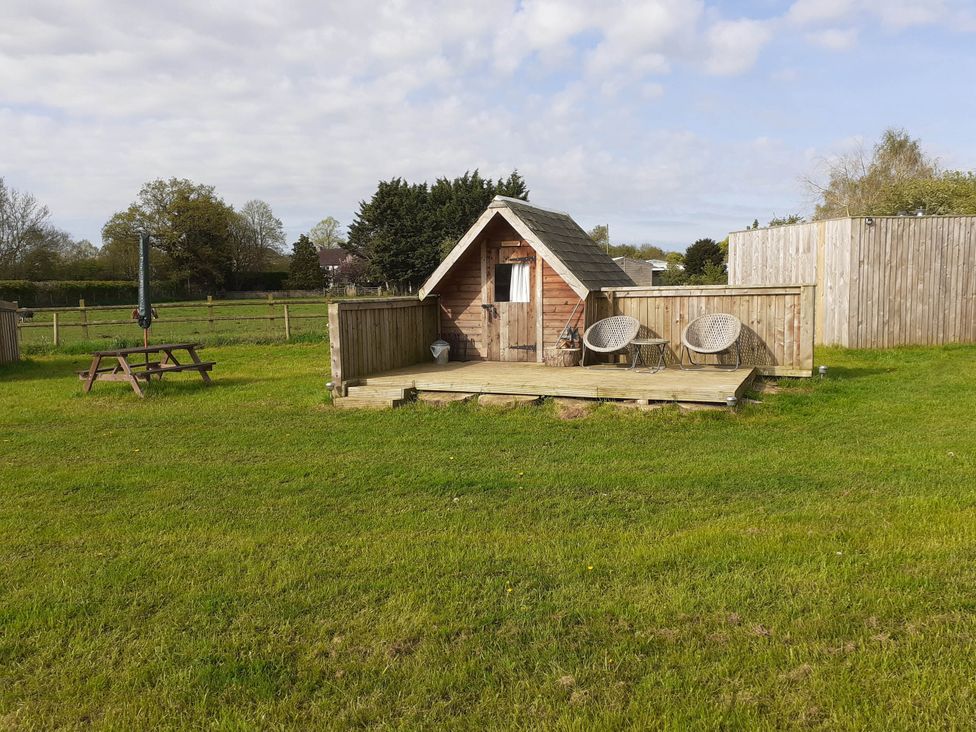 A garden with a wooden cabin and picnic table at Glamping at the Retreat Wiltshire Christian Malford