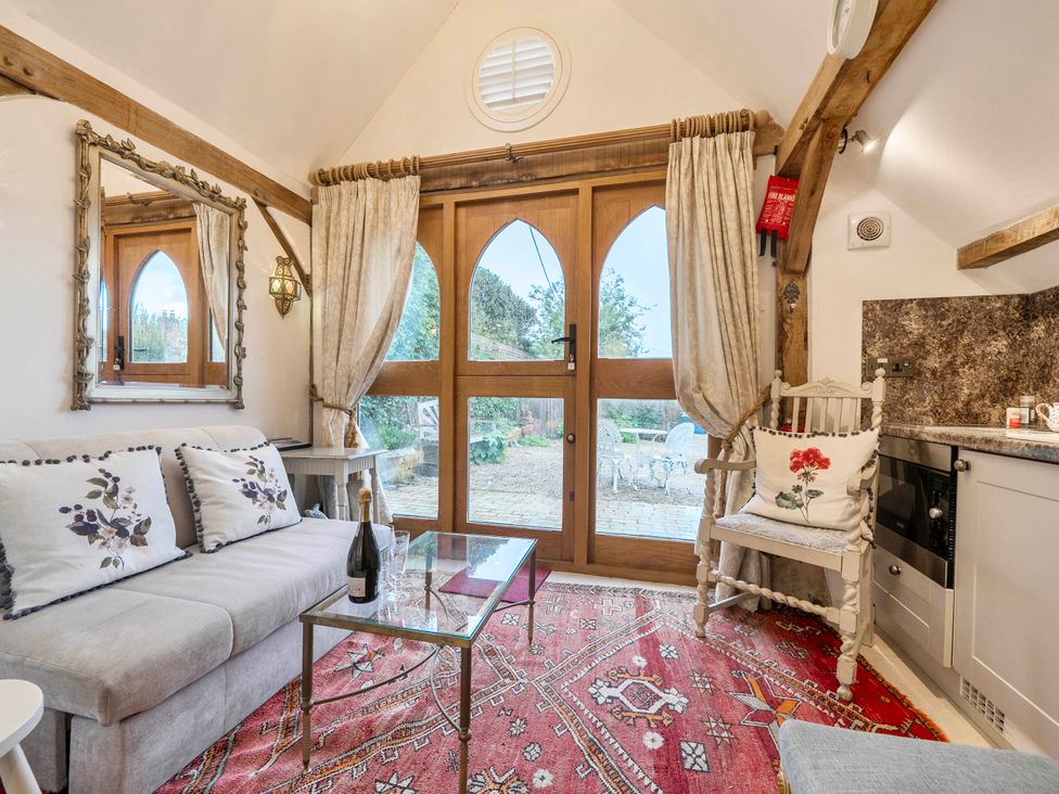 A living room with a sofa, glass table, and kitchenette at Bramble Bank 'CartShed'-1 Bed Cottage-Sleeps 2 Henley-On-Thames