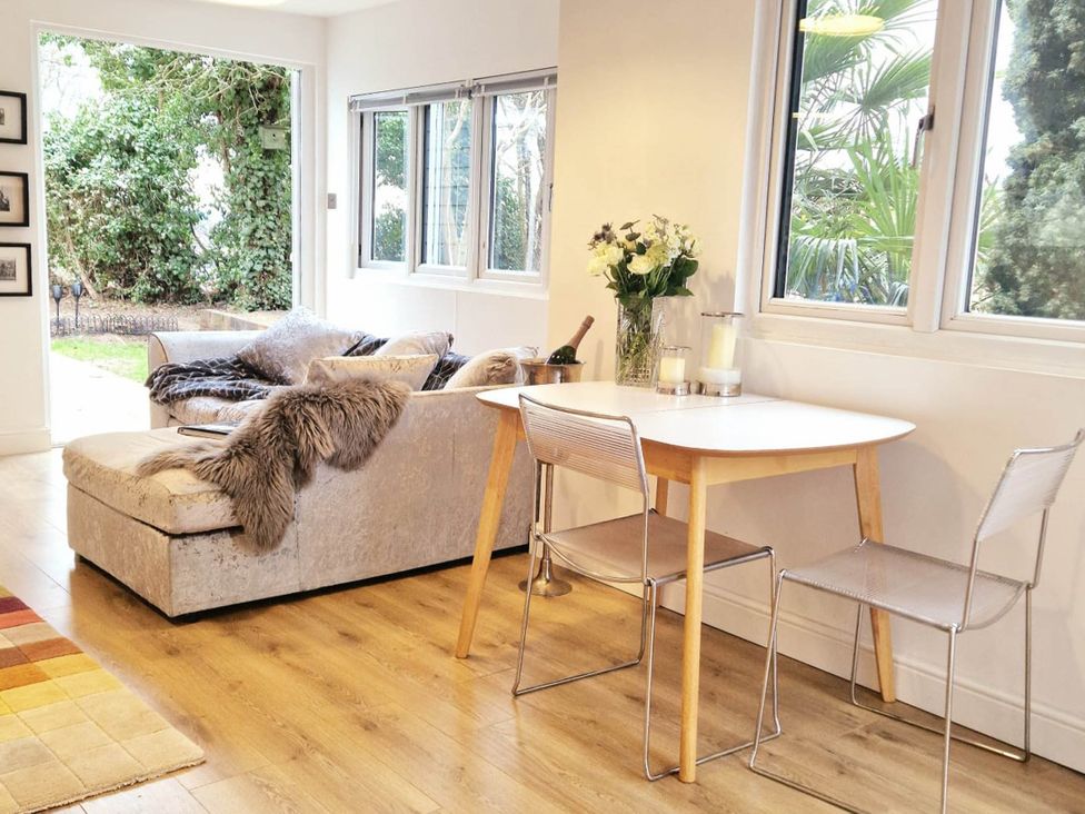 A living room with a sofa and a dining table at 1 Bed Cottage-Museum View-Garden-Free Parking, Weybridge, Surrey