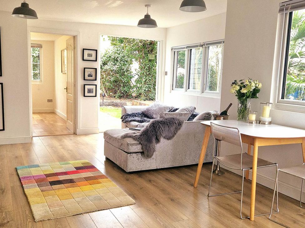 A living room with a sofa and dining table at 1 Bed Cottage-Museum View-Garden-Free Parking in Weybridge, Surrey