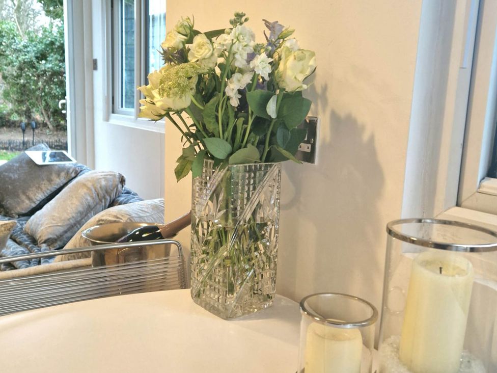 A vase of flowers and candles on a table at 1 Bed Cottage-Museum View-Garden-Free Parking in Weybridge, Surrey