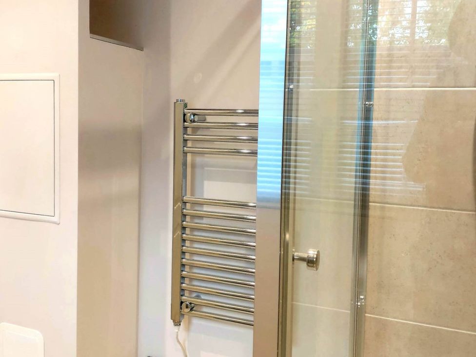 A bathroom with a towel radiator and a glass shower door at 1 Bed Cottage-Museum View-Garden-Free Parking, Weybridge, Surrey