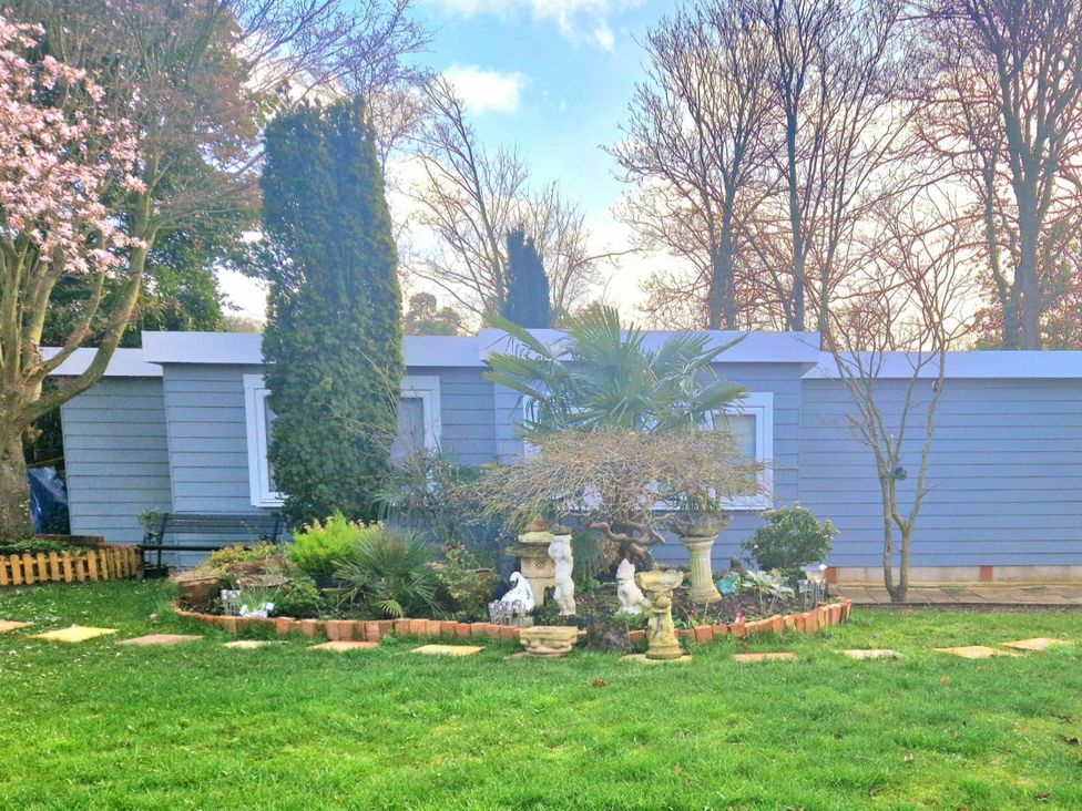 A house with garden features including trees and statues at 1 Bed Cottage-Museum View-Garden-Free Parking in Weybridge, Surrey