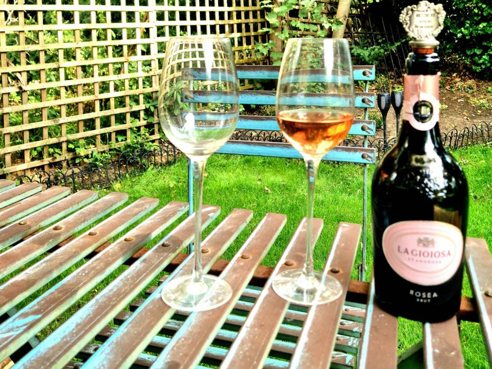 Wine glasses and a bottle on a table in a garden at 1 Bed Cottage-Museum View-Garden-Free Parking Weybridge, Surrey