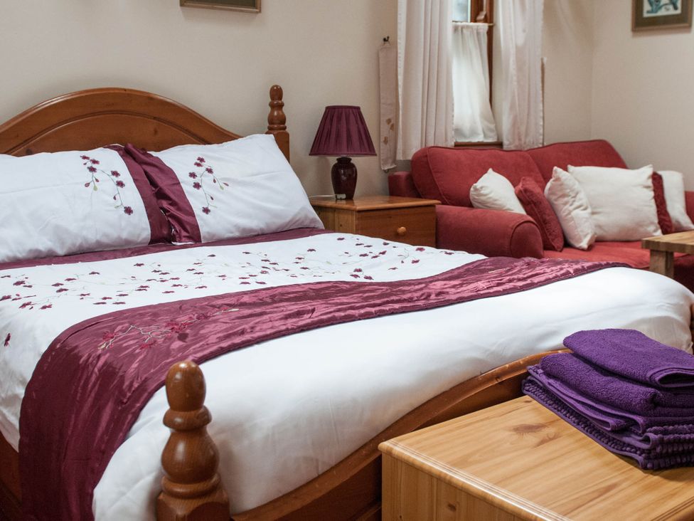 A bedroom with a bed and sofa at Beautiful 1-Bed Cottage in Trellech