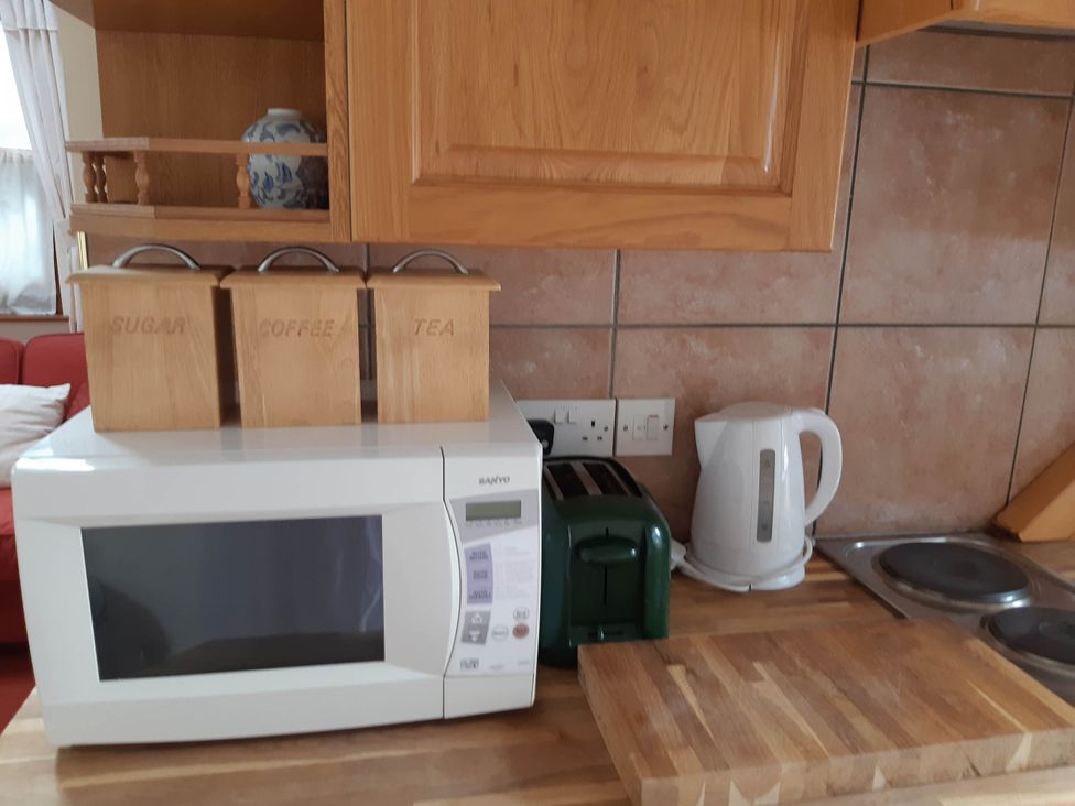 A kitchen with a microwave, toaster, kettle and storage containers at Beautiful 1-Bed Cottage in Trellech