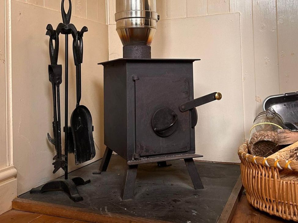 A wood stove and fireplace tools at Cozy Cabin Retreat near Chepstow