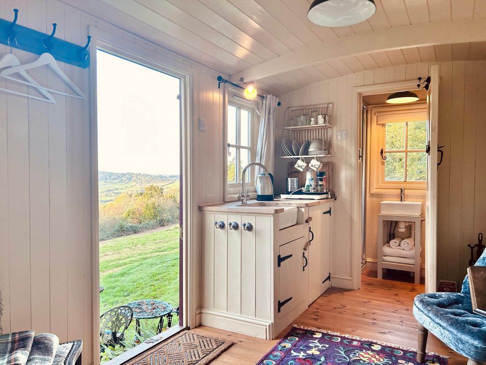 A kitchen with a sink and shelves at Cozy Cabin Retreat near Chepstow