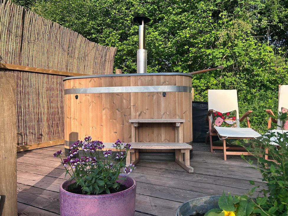 An outdoor area with a hot tub and lounge chairs at Cozy Cabin Retreat near Chepstow