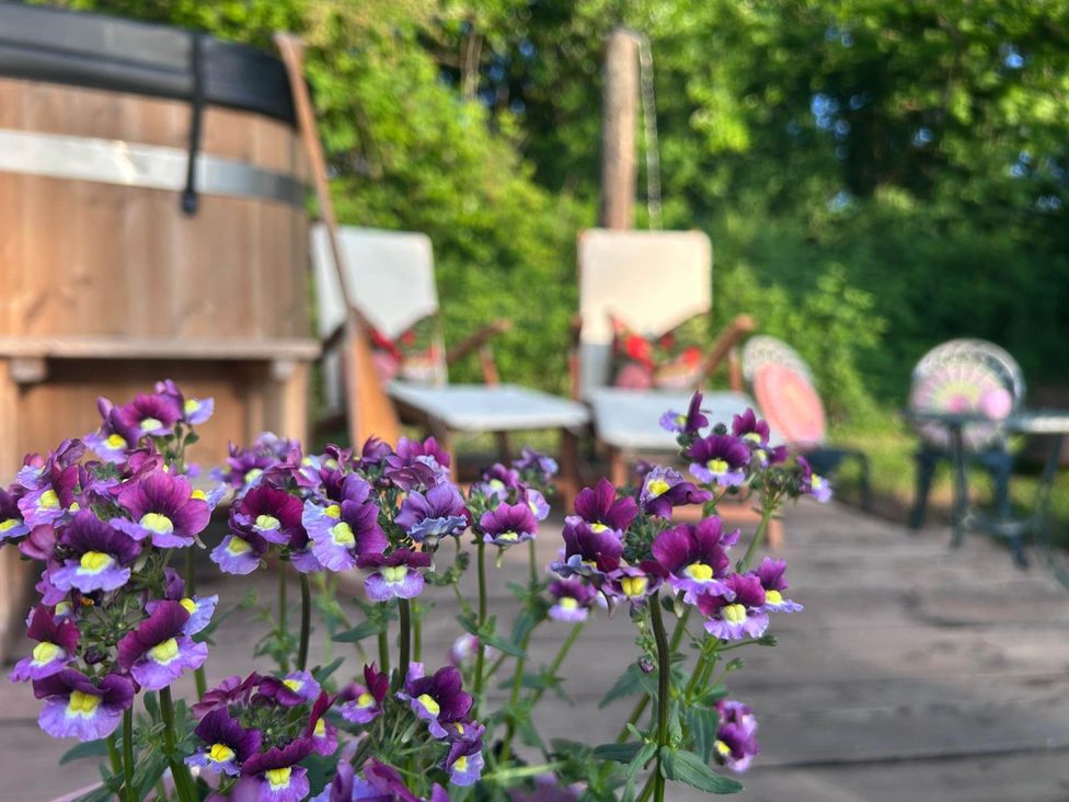 A deck with flowers and a hot tub at Cozy Cabin Retreat near Chepstow