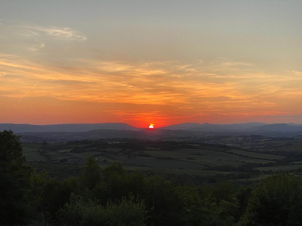 A scenic view of a sunset over hills and valleys at Cozy Cabin Retreat near Chepstow
