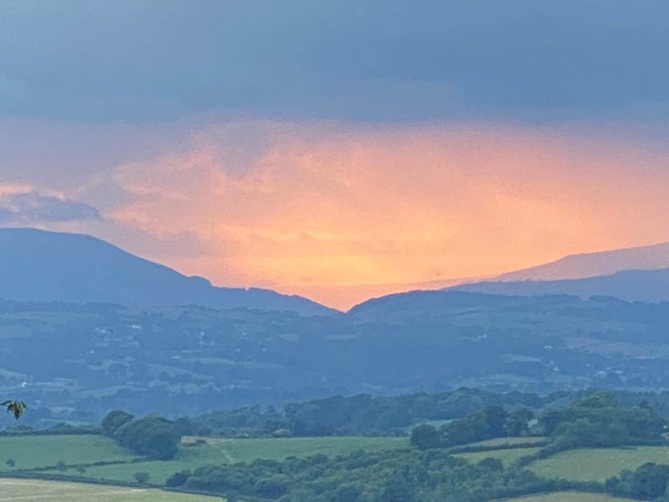 A view of mountains and fields under a sunset sky at Cozy Cabin Retreat near Chepstow