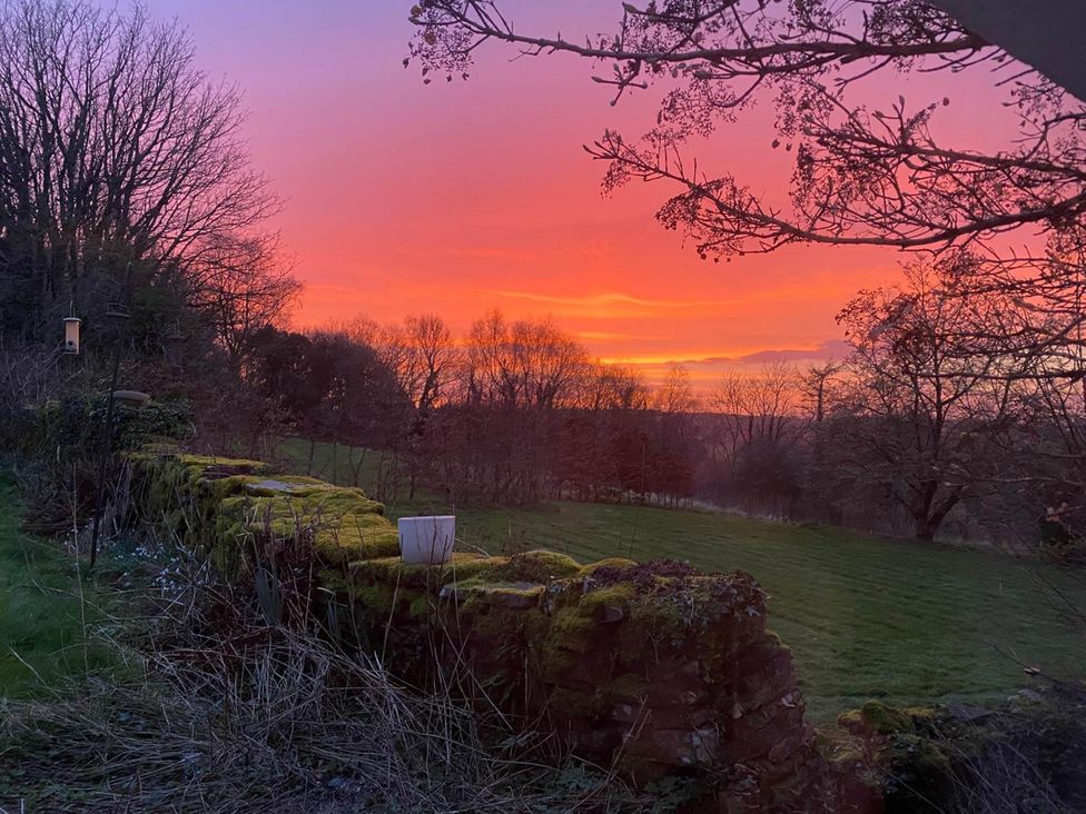 A sunset view with grass and a stone wall at Cozy Cabin Retreat near Chepstow