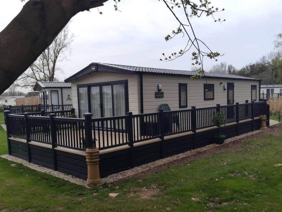 An outdoor area with a lodge and decking at 2 Bed Lodge Sleeps 4 - Pet Welcome - Fireplace in Cirencester