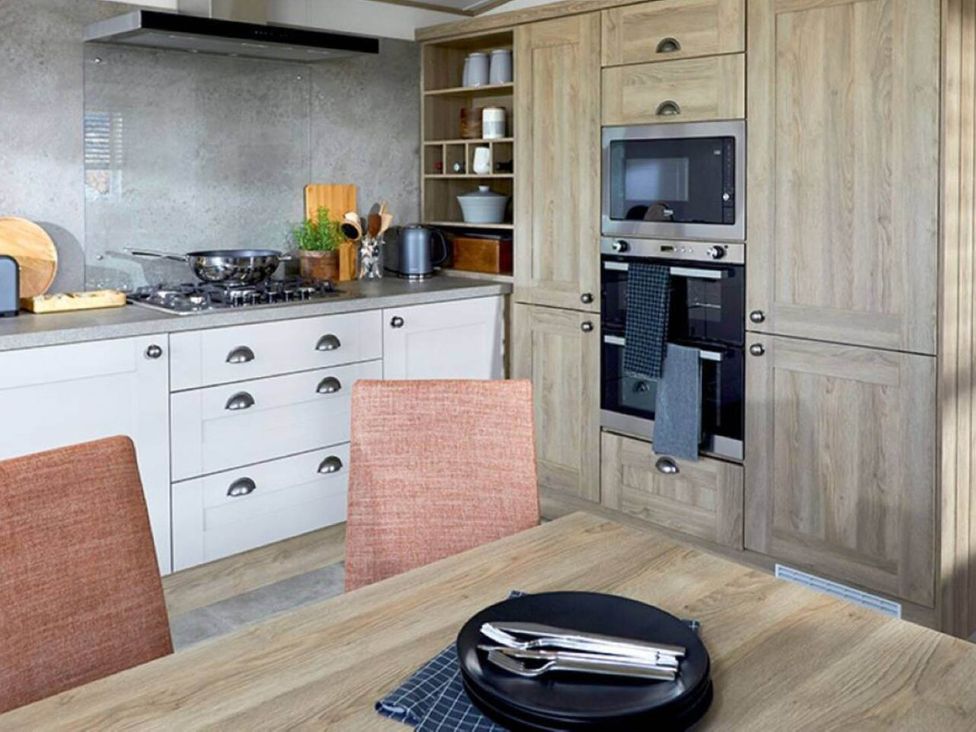 A kitchen with stove, oven, cabinets and dining table at 2 Bed Lodge Sleeps 4 - Pet Welcome - Fireplace, Cirencester