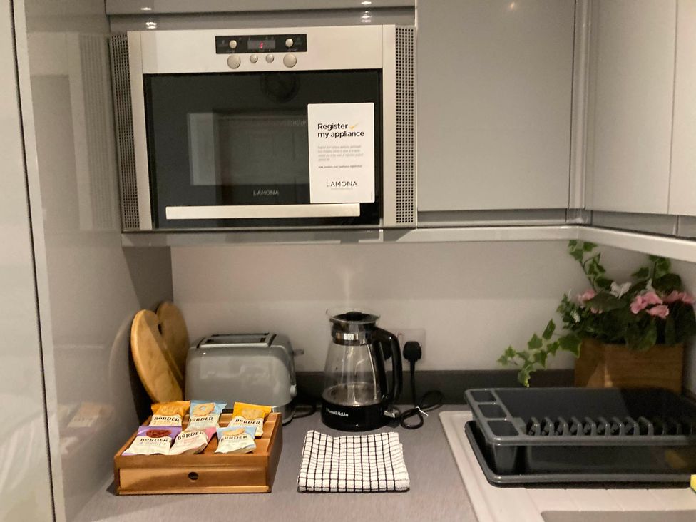 A kitchen with a microwave, toaster, kettle, and various kitchen items at Beautiful 1-Bed studio in Penrith