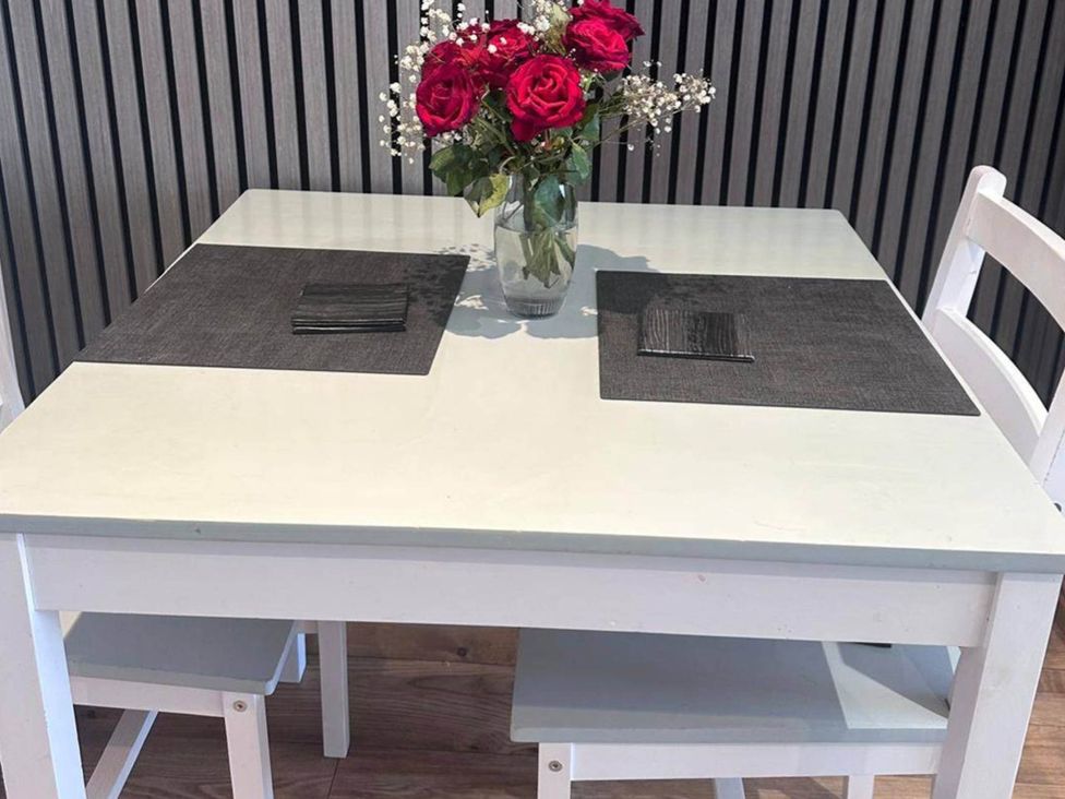 A table with a vase of roses and placemats at Beautiful 1-Bed studio in Penrith
