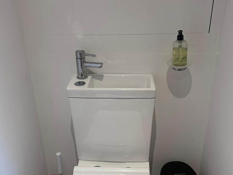 A toilet and sink with a soap dispenser in a bathroom at Beautiful 1-Bed studio in Penrith