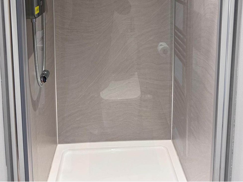 A shower area with a showerhead and modern tiles at Beautiful 1-Bed studio in Penrith