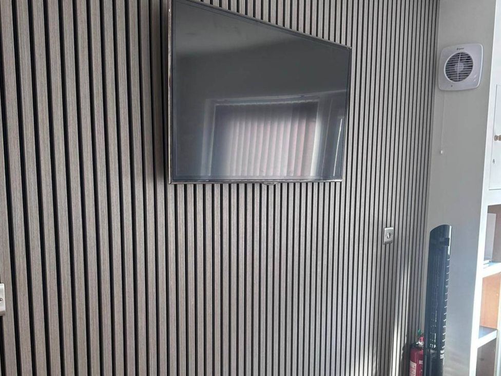 A living room with a television mounted on a wall at Beautiful 1-Bed studio in Penrith