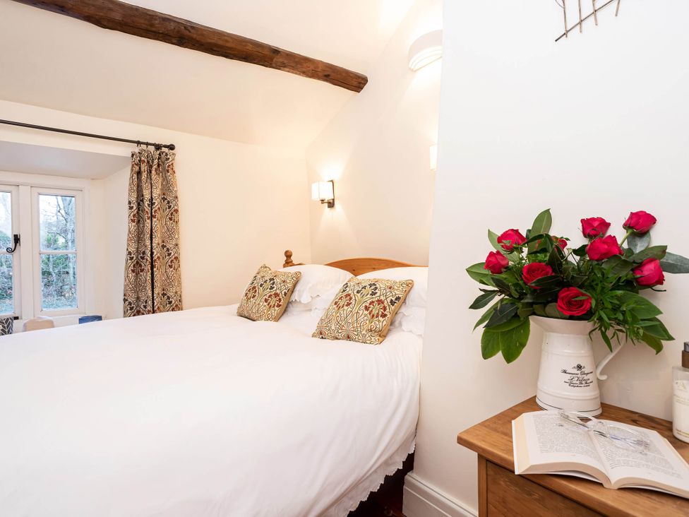 A bedroom with a bed and flowers on a table at Ingleton 2-Bed Cottage, Sleeps 4, Pet Ok & Parking in Ingleton