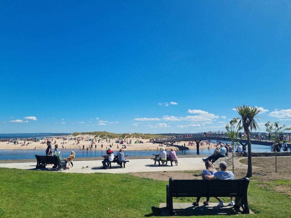 A beach scene with people and benches at The Coal Office in Aberlour