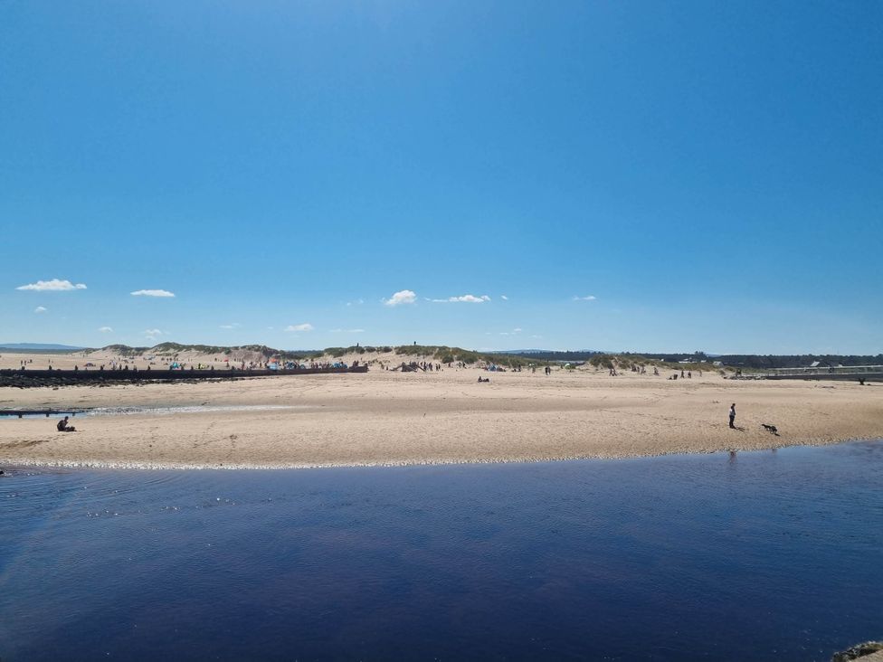 A beach scene with people and water at The Coal Office, Aberlour