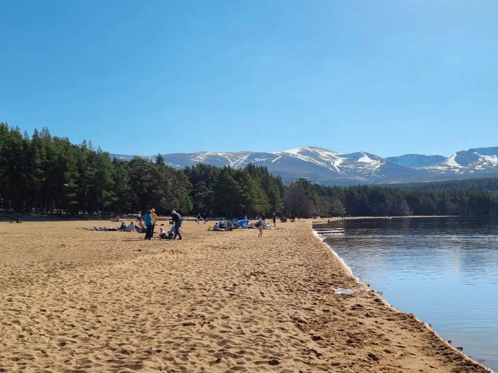 A beach with people and trees near water at The Coal Office, Aberlour