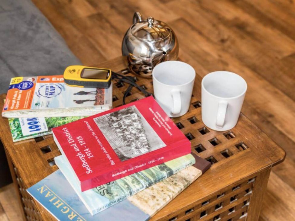 A living room with books and mugs on a wooden table at Sedbergh Penthouse - KingBed - Tv - Wifi Sedbergh