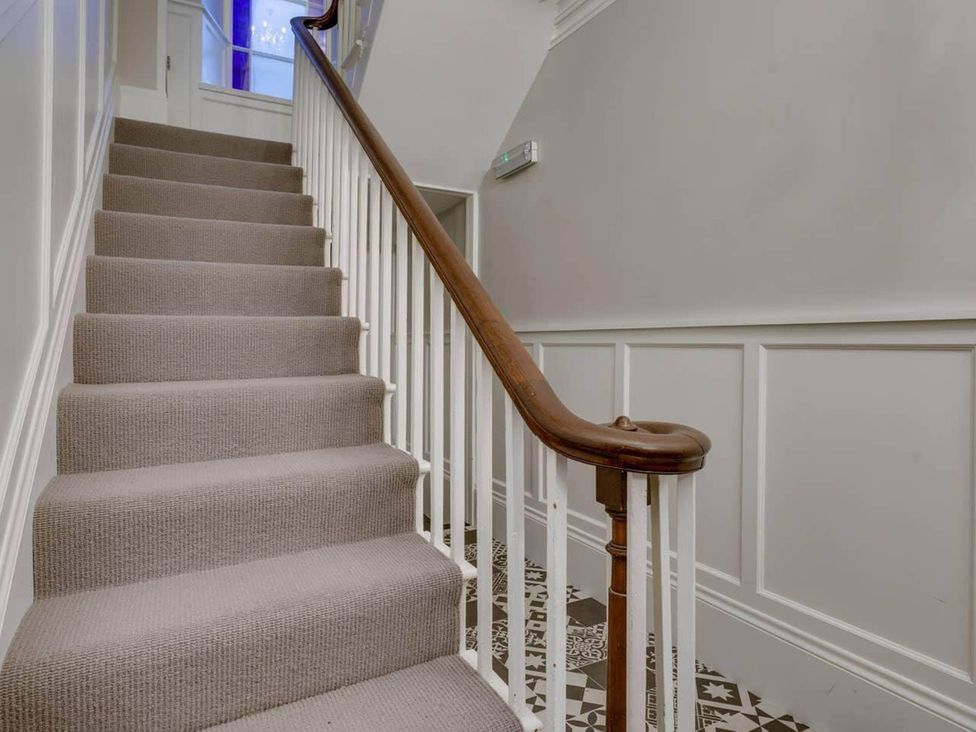 A staircase with carpet and a wooden handrail at Sedbergh Penthouse - KingBed - Tv - Wifi in Sedbergh