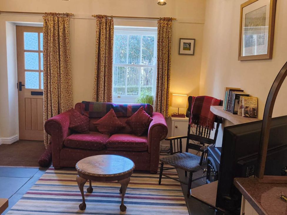 A living room with a couch and tables at Cosy Cottage for two in the centre of Sedbergh