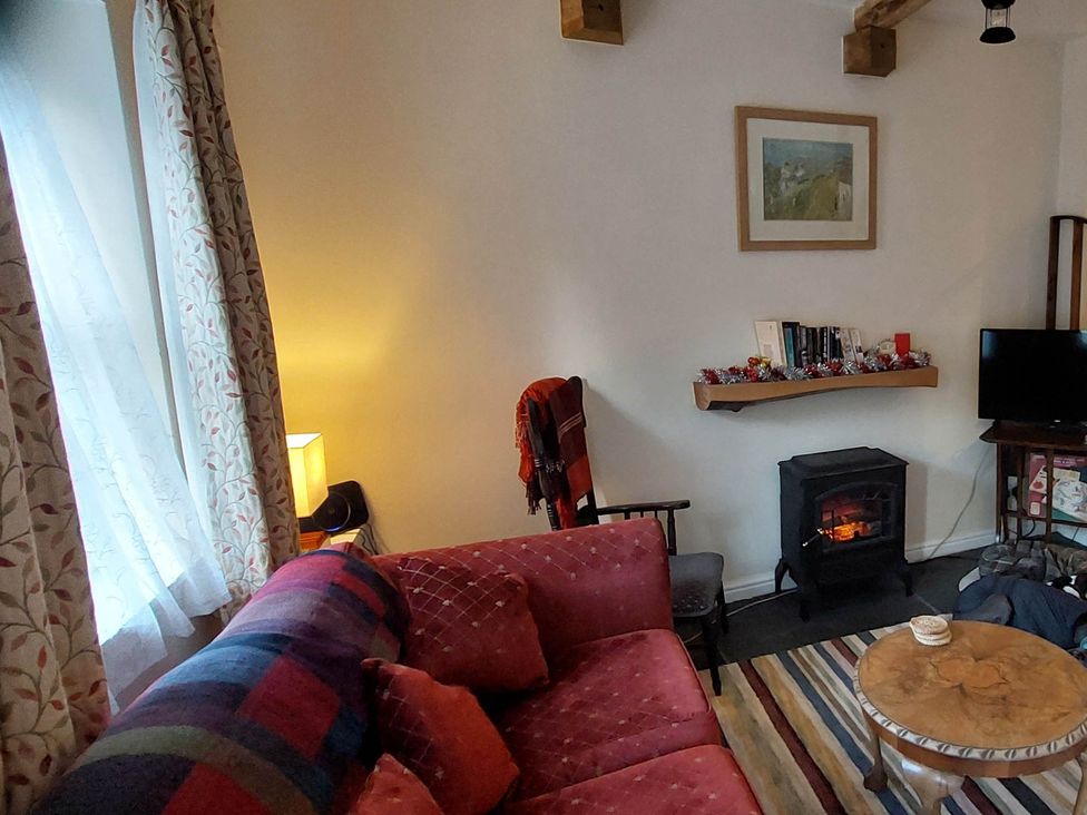 A living room with a sofa and a fireplace at Cosy Cottage for two in the centre of Sedbergh