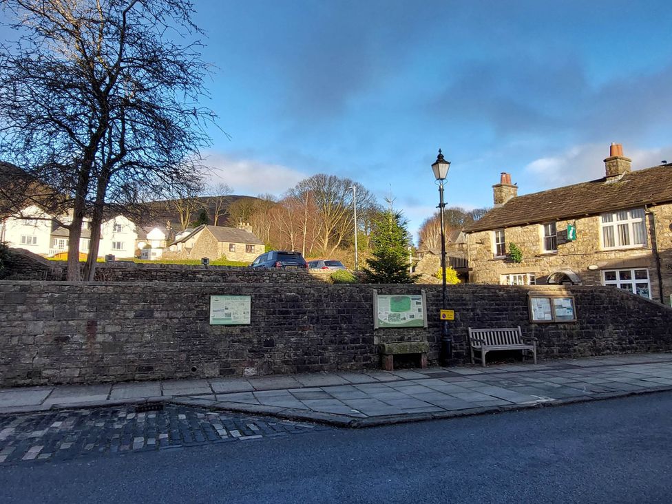 An outdoor scene with a stone wall, trees and buildings at Cosy Cottage for two in the centre of Sedbergh