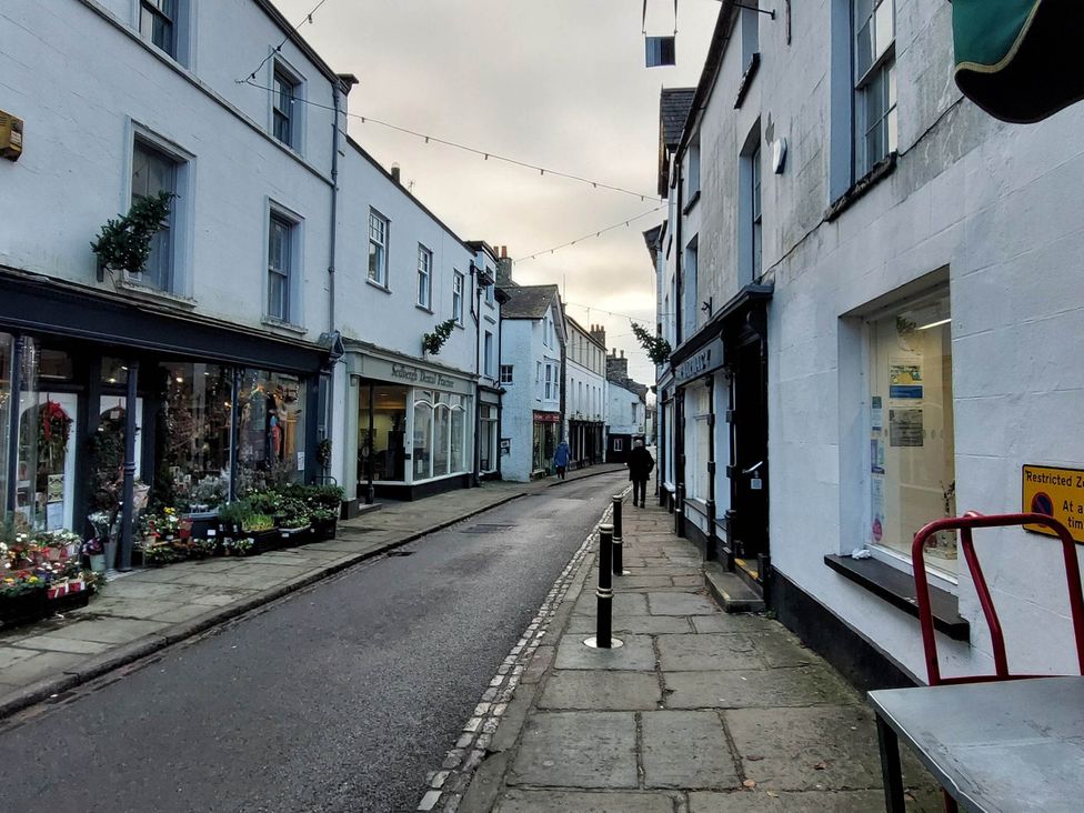A street view with shops and a sidewalk at Cosy Cottage for two in the centre of Sedbergh