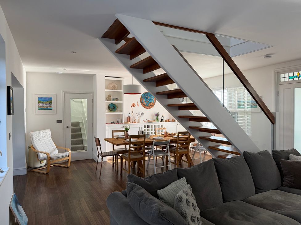 A living room with a staircase and dining area at Lorrell in Salcombe