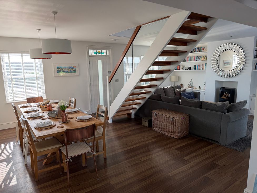 A dining room with a table set for meals and a staircase at Lorrell Salcombe