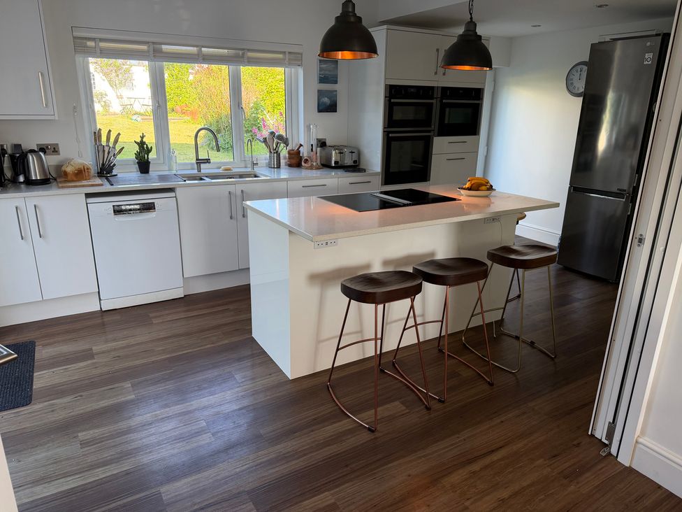 A kitchen with an island and stools at Lorrell in Salcombe
