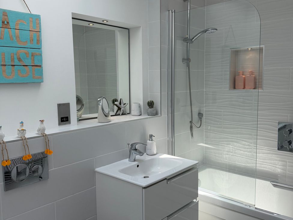 A bathroom with a sink, mirror, shower, and bathtub at Lorrell in Salcombe