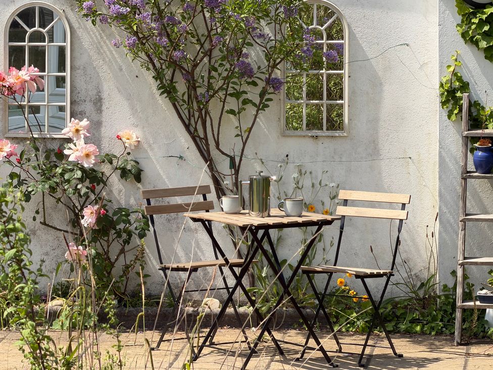A garden with a table and chairs surrounded by flowers at Lorrell in Salcombe