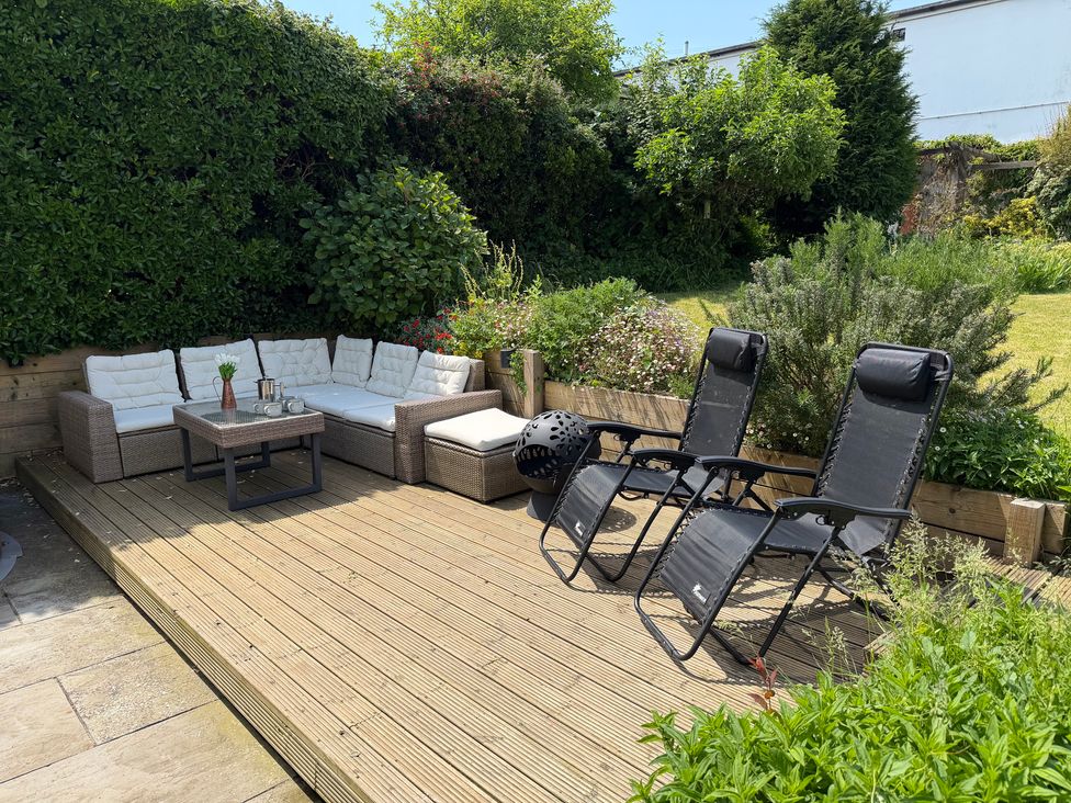 A garden with a sofa, coffee table, and sun loungers at Lorrell in Salcombe